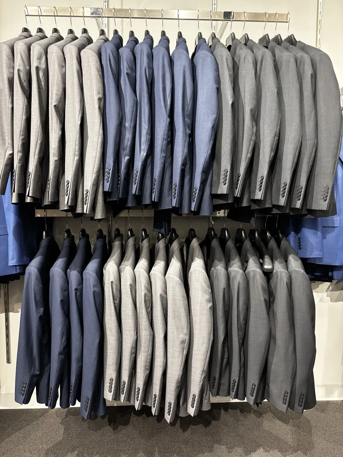 Blue and gray suits displayed on racks in the Modern Suit & Dress store
